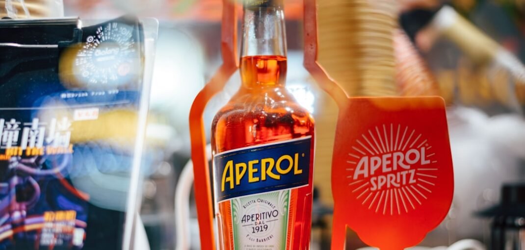 A classic Aperol Spritz cocktail in a wine glass with ice, orange slice, and sparkling wine, representing the perfect autumn aperitif