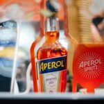 A classic Aperol Spritz cocktail in a wine glass with ice, orange slice, and sparkling wine, representing the perfect autumn aperitif