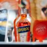 A classic Aperol Spritz cocktail in a wine glass with ice, orange slice, and sparkling wine, representing the perfect autumn aperitif