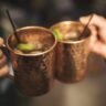 person holding stainless steel spoon in brown ceramic mug