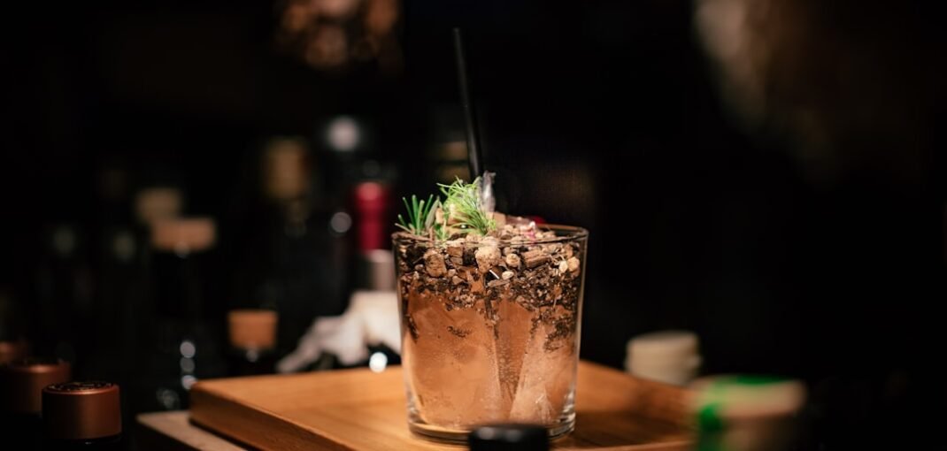 A close-up of juniper berries and botanicals used in gin production, with a clear gin bottle in the background