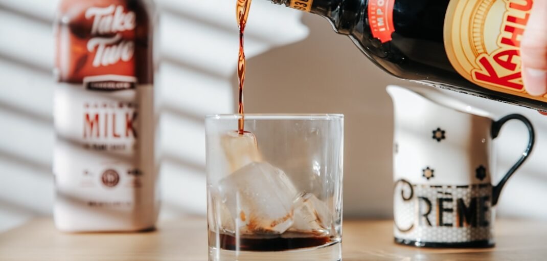 A bottle of Kahlúa coffee liqueur next to a glass of dark liquid, showcasing the liqueur's deep brown colour