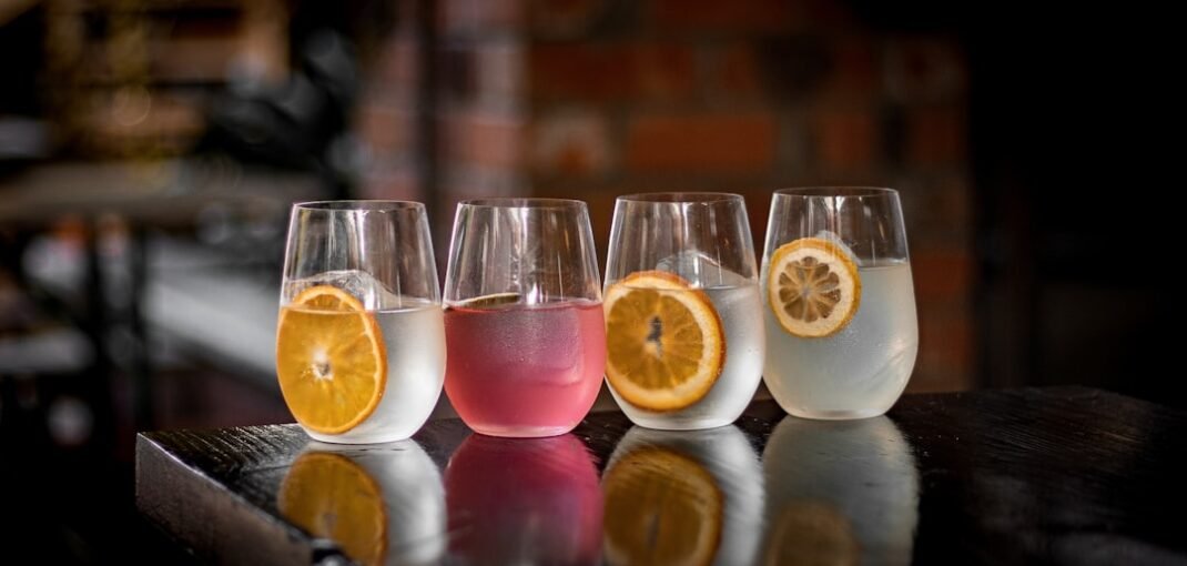 A glass of Fever Tree tonic water poured over ice with a slice of lime, photographed on a dark winter table setting in New Zealand