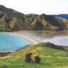 A glass of amber whisky on a wooden table with a winter New Zealand backdrop, perfect for a beginner's guide to whisky