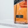 Bottle of Johnnie Walker Black Label Scotch whisky on a dark wooden surface with a glass of whisky neat