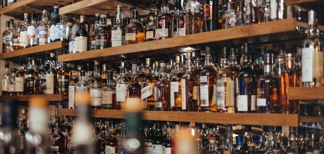 A glass of amber single malt whisky beside a bottle of blended Scotch, comparing single malt vs blended whisky styles