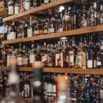 A glass of amber single malt whisky beside a bottle of blended Scotch, comparing single malt vs blended whisky styles