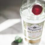 Tanqueray Gin cocktail served in a crystal glass with juniper berries and a lemon twist on a dark winter background