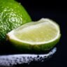 A vodka lemon lime cocktail in a tall glass with ice, fresh lemon and lime slices, and soda, served on a wooden surface