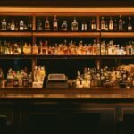 A home bar whisky collection with several bottles of Scotch, bourbon and Irish whisky arranged on a wooden shelf